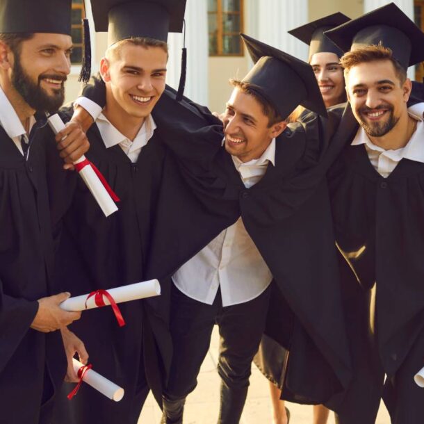 A group of seven students holding their diplomas in graduation regalia and posing together at The Atrium Event Space near Southfield, Michigan (MI)