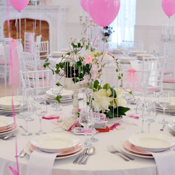 Table in a ballroom with white tablecloths, dinnerware, and glassware with pink balloons for a Sweet 16 at The Atrium Event Space near Southfield, Michigan (MI)