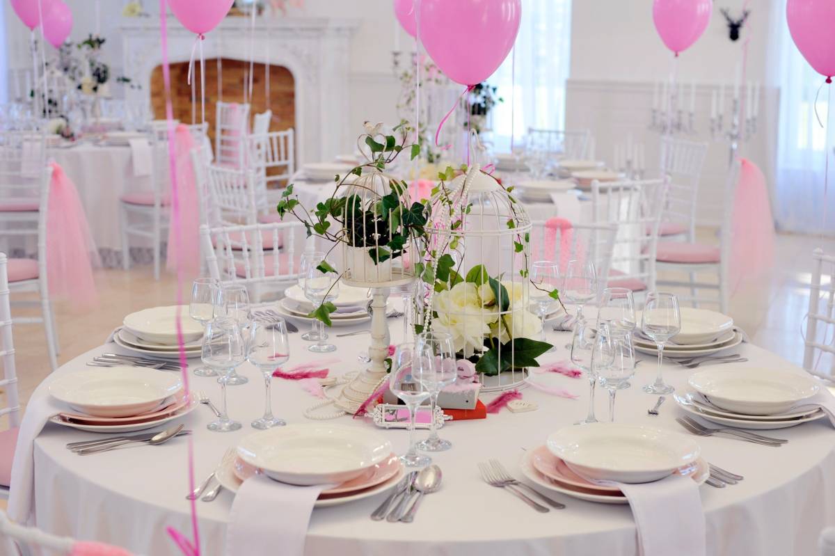Table in a ballroom with white tablecloths, dinnerware, and glassware with pink balloons for a Sweet 16 at The Atrium Event Space near Southfield, Michigan (MI)