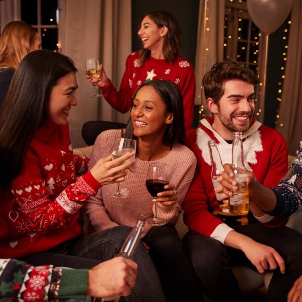 Seven team members wearing holiday sweaters, laughing, and chatting during a corporate holiday party at The Atrium Event Space near Southfield, Michigan (MI)