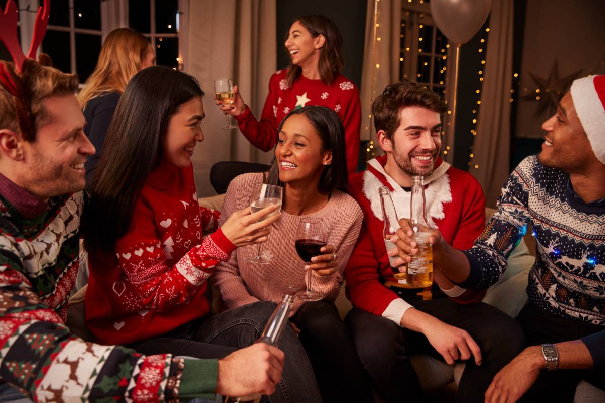 Seven team members wearing holiday sweaters, laughing, and chatting during a corporate holiday party at The Atrium Event Space near Southfield, Michigan (MI)