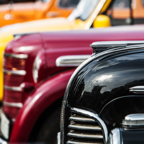 Image of four colorful, vintage, and luxury vehicles at an automotive showcase near Detroit, MI