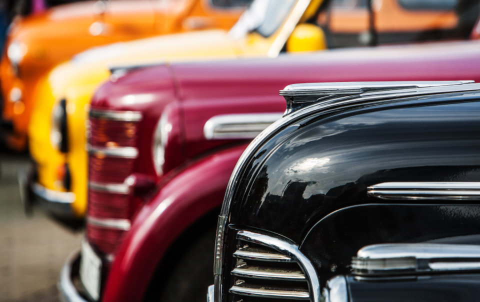 Image of four colorful, vintage, and luxury vehicles at an automotive showcase near Detroit, MI