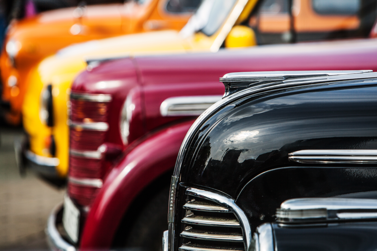 Image of four colorful, vintage, and luxury vehicles at an automotive showcase near Detroit, MI
