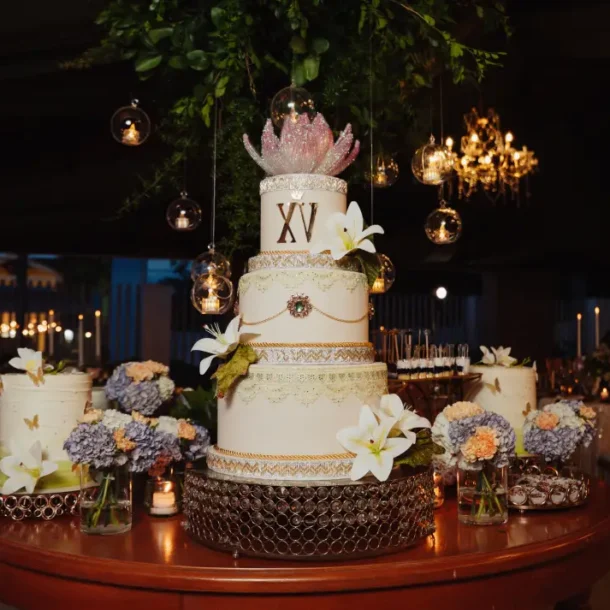 A three-tiered cake with Roman numerals XV at an event venue hosting a quinceañera