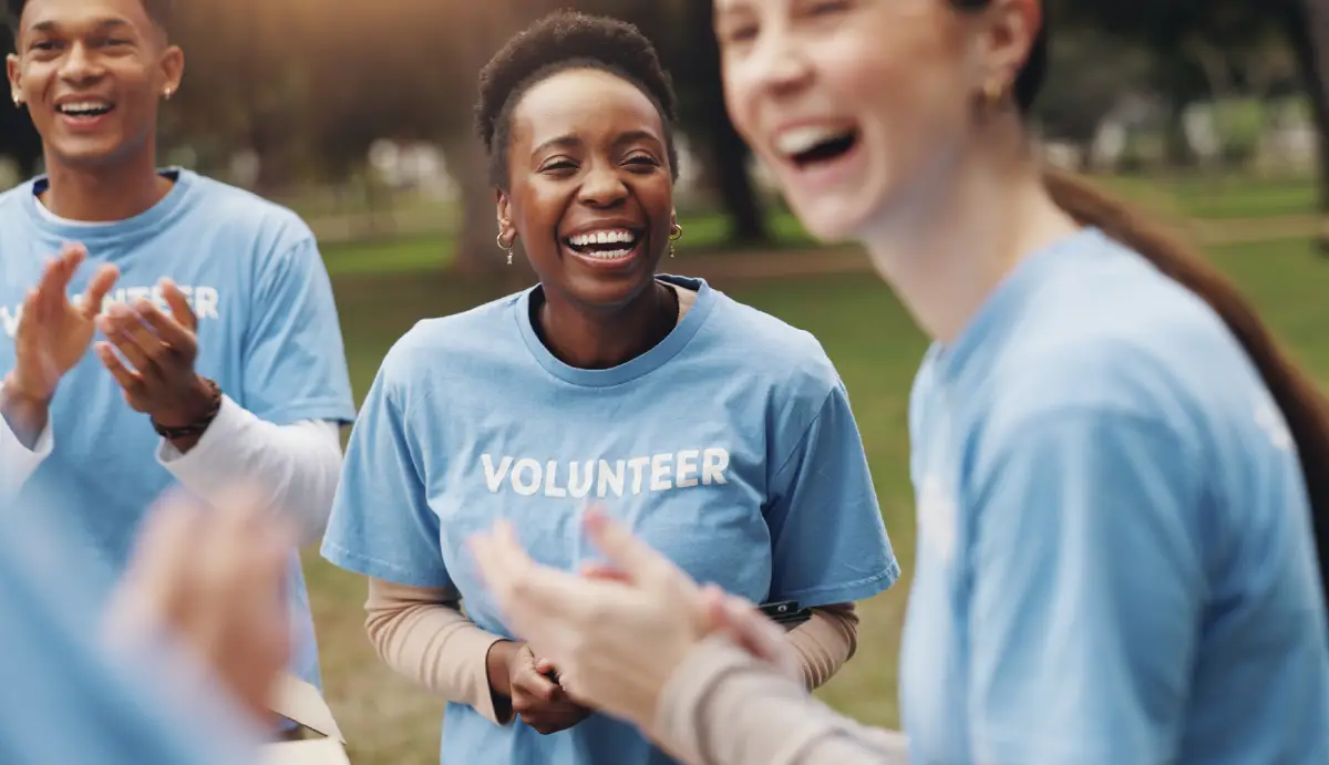 Three volunteers at a community event wearing light blue shirts with white font reading "Volunteer"