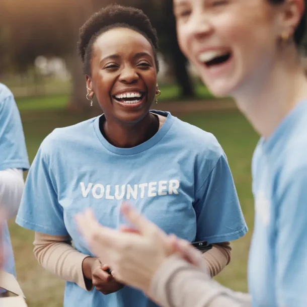 Three volunteers at a community event wearing light blue shirts with white font reading "Volunteer"